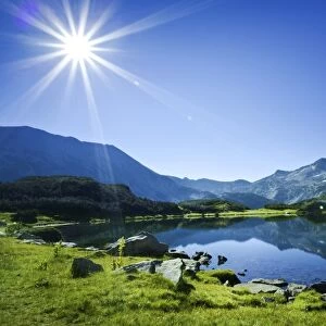 Muratov Lake against blue sky and bright sun in Pirin National Park, Bulgaria